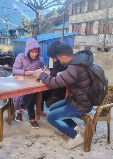 Researchers sit together at a table outside, examining their research