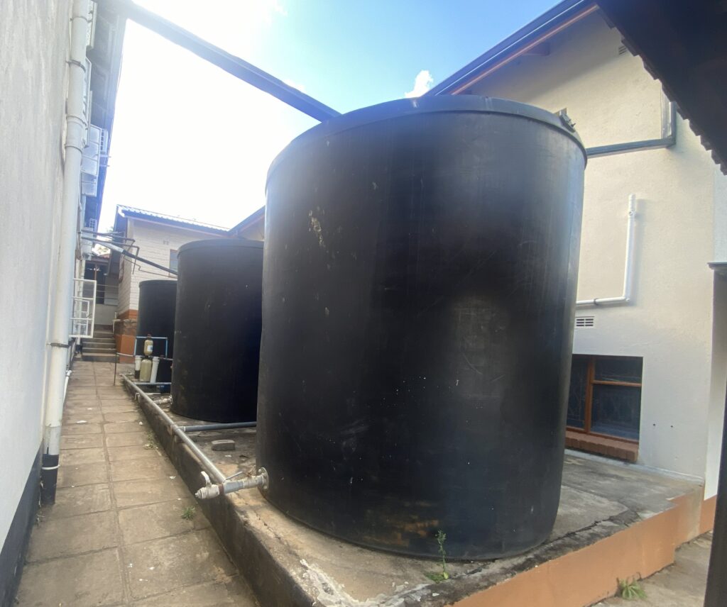 Three large black barrels fed by pipes from the adjoining roof