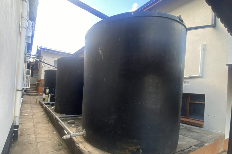 Three large black barrels fed by pipes from the adjoining roof