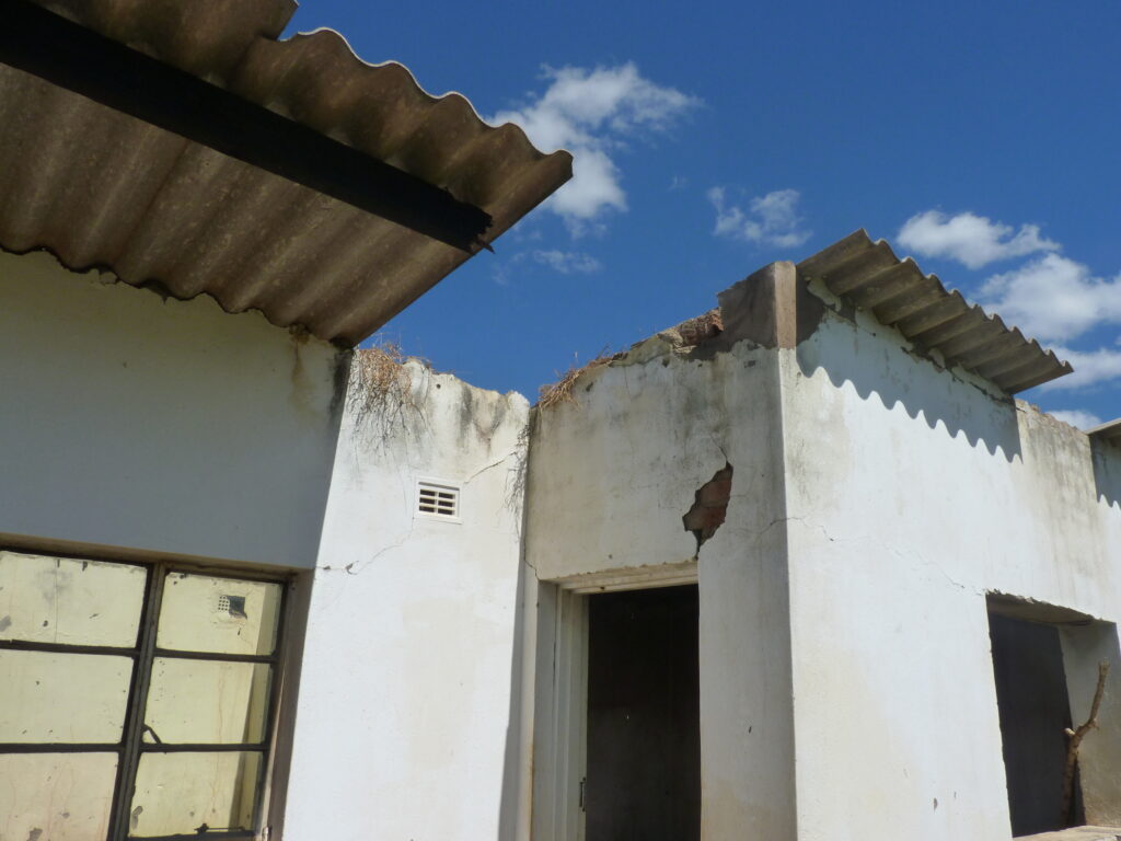 A white walled building with a missing roof and signs of damage